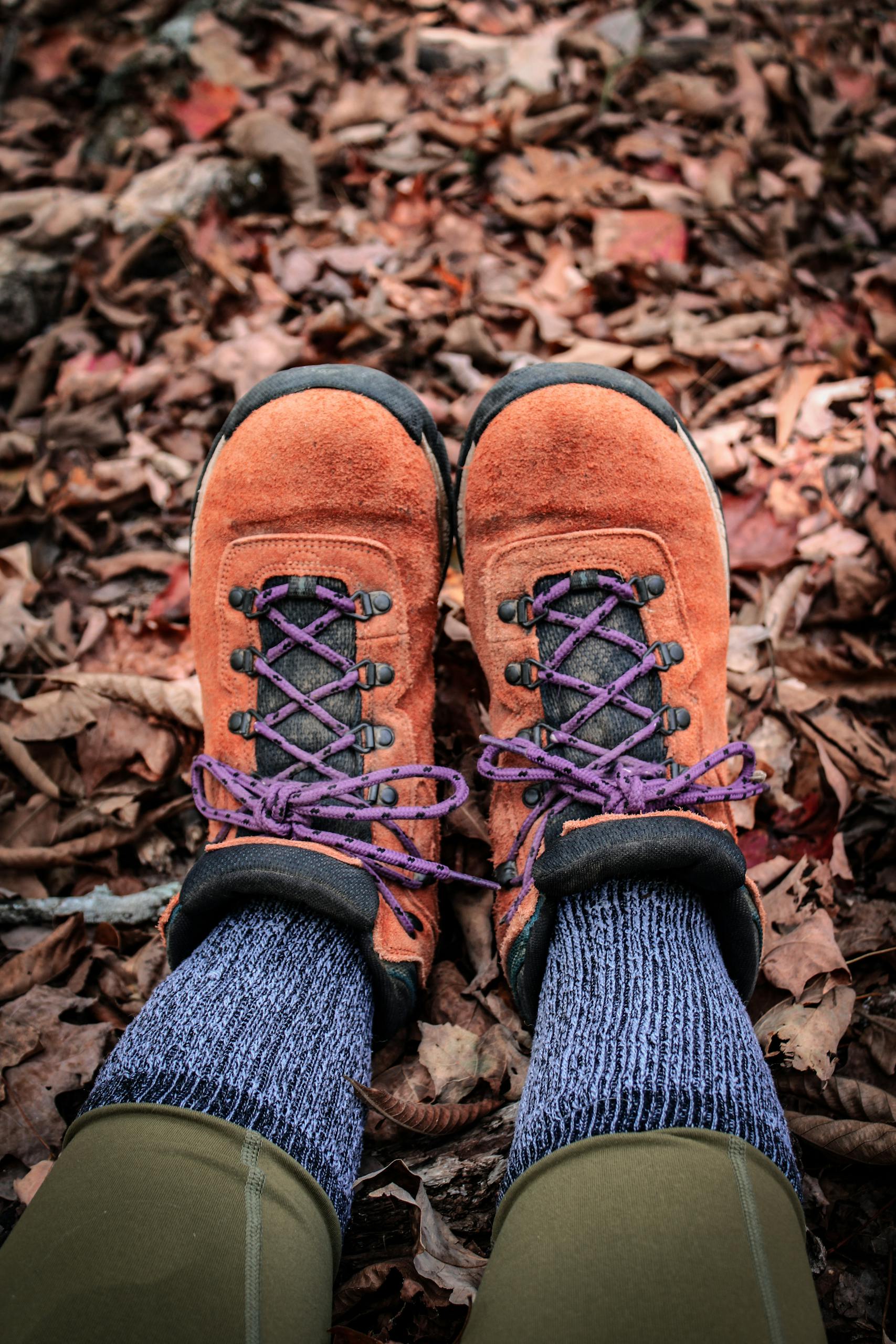 Close-up of hiking boots on fallen leaves, perfect for fall adventures.