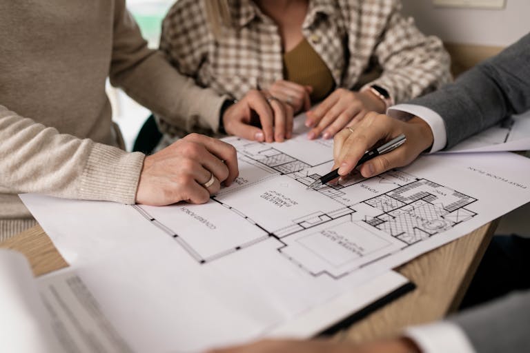 Group examining house floor plans with a real estate agent, making forever home decisions.