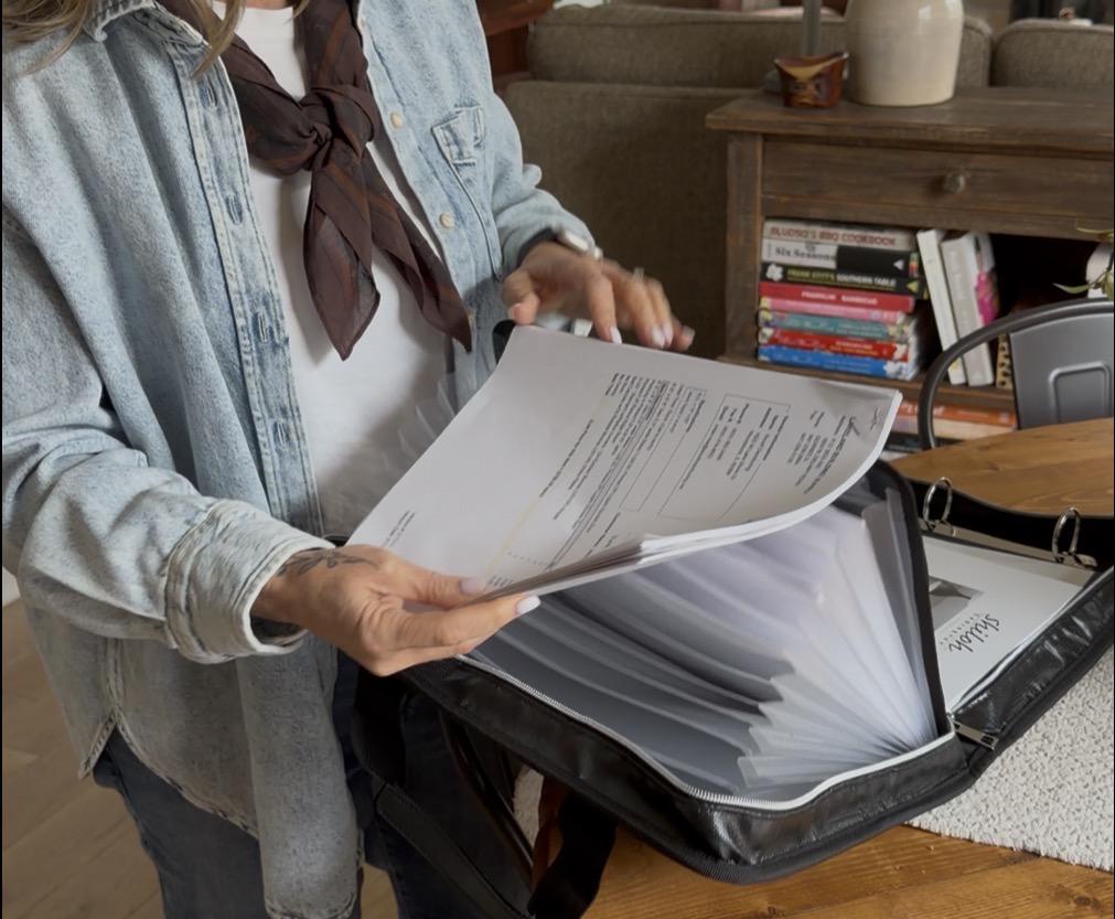 hands paging through a binder that contains an acordian file, reading paperwork