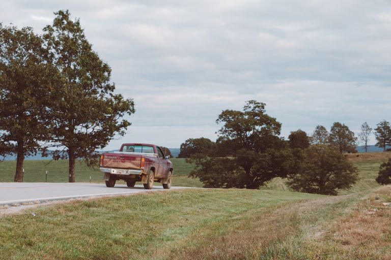 The pickup truck phase of moving in midlife: an old pick up truck drives down a country road
