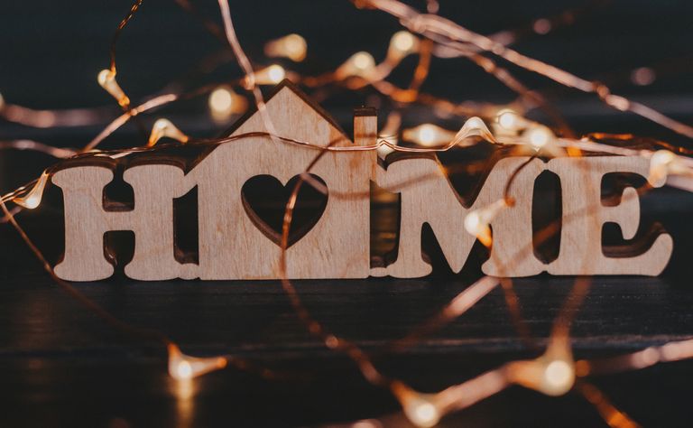 Warm and inviting wooden 'HOME' sign surrounded by glowing fairy lights. House feel like a home.