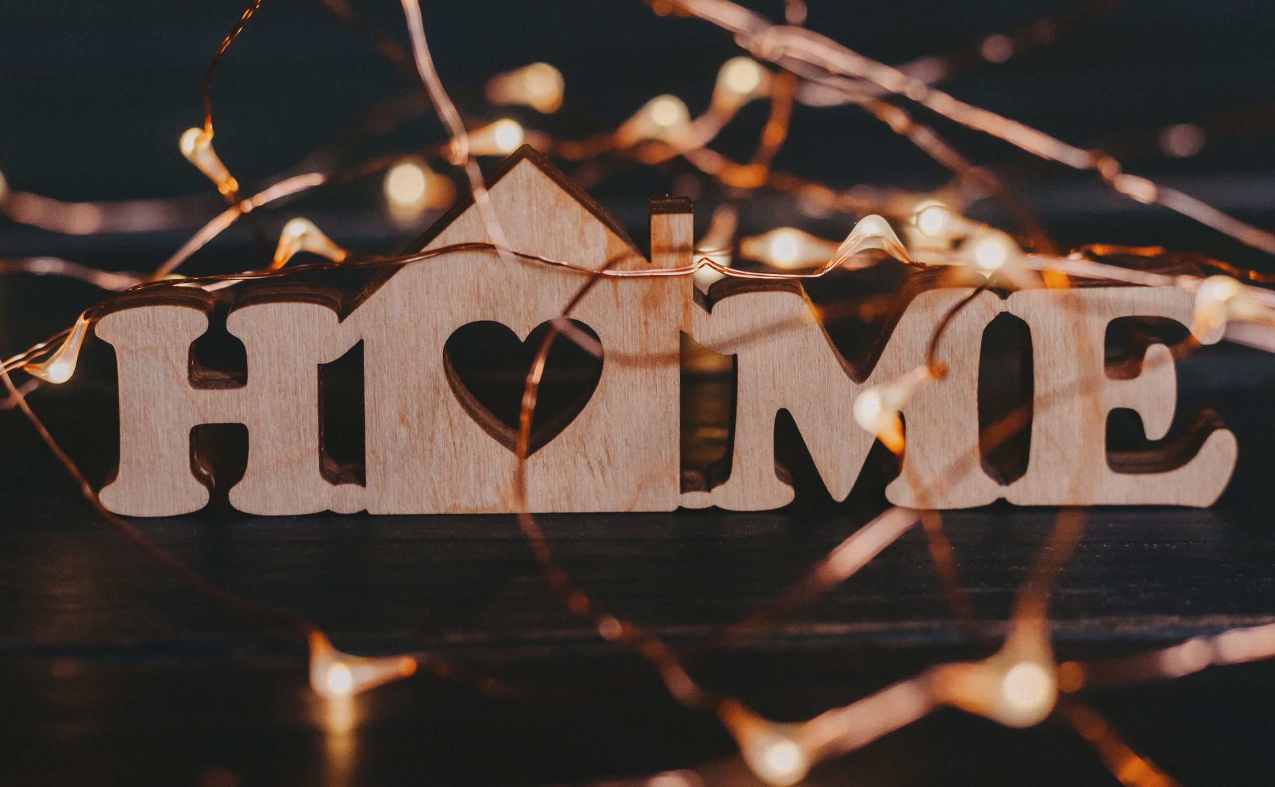 Warm and inviting wooden 'HOME' sign surrounded by glowing fairy lights. House feel like a home.